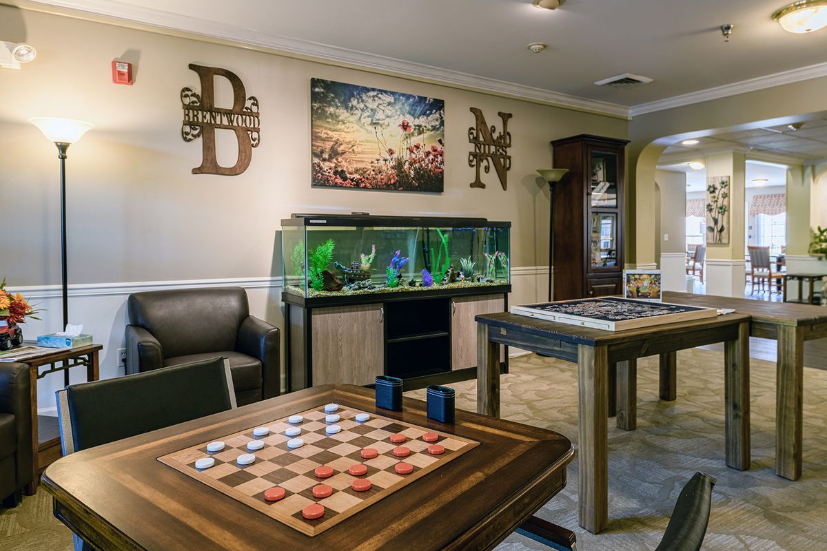 A cozy game room featuring checkers boards and an illuminated aquarium.