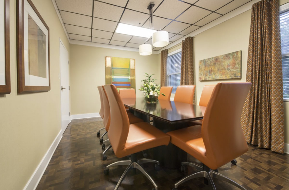 A modern conference room with a large meeting table and orange chairs.