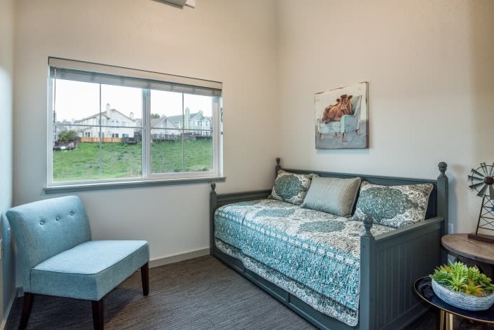 A cozy bedroom with a daybed and a window overlooking the outdoors.