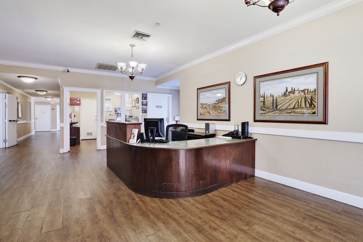 A reception area with a wooden desk and paintings on the wall.