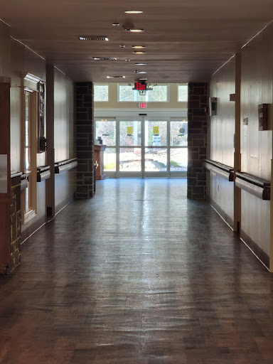 A bright and spacious hallway with wooden flooring leading to an exit.