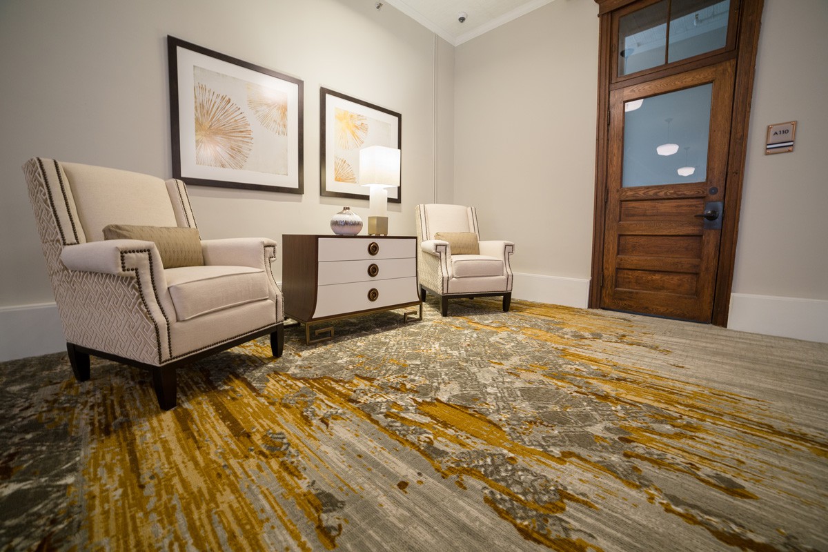 A cozy room with two armchairs, a side table, and abstract art on the walls.