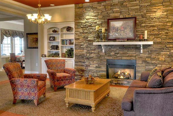 A cozy living room with a stone fireplace and comfortable seating.