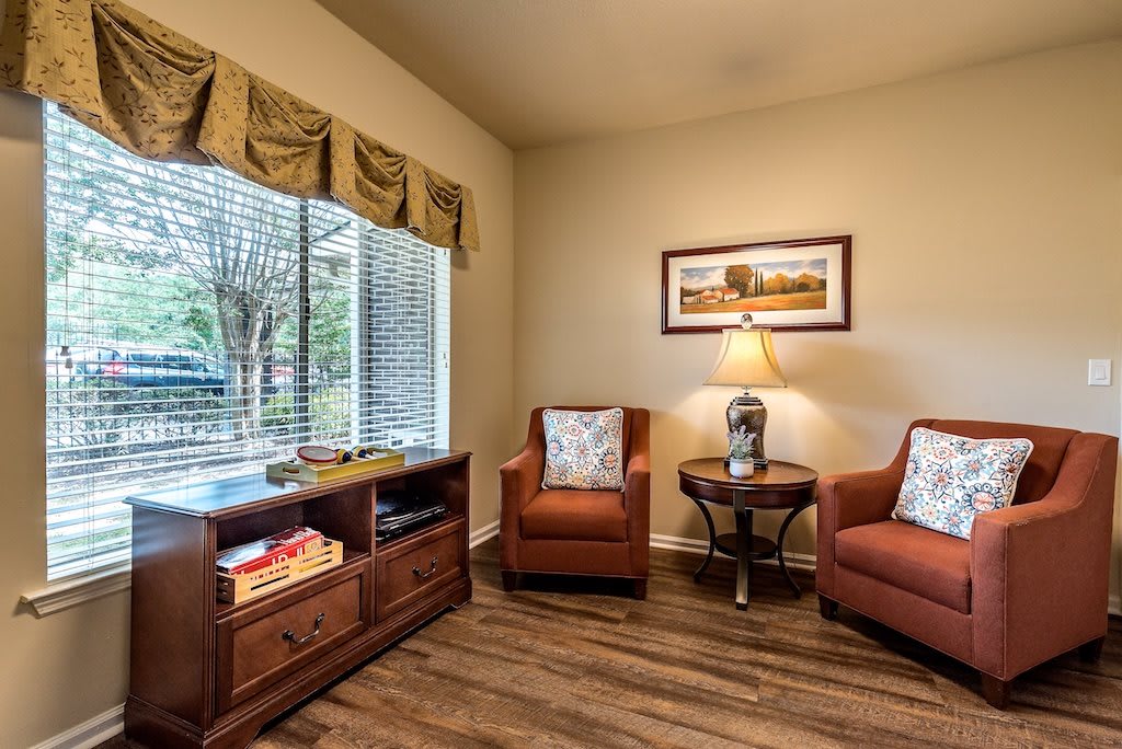 A cozy living room seating area with two armchairs and a small table under warm lighting.