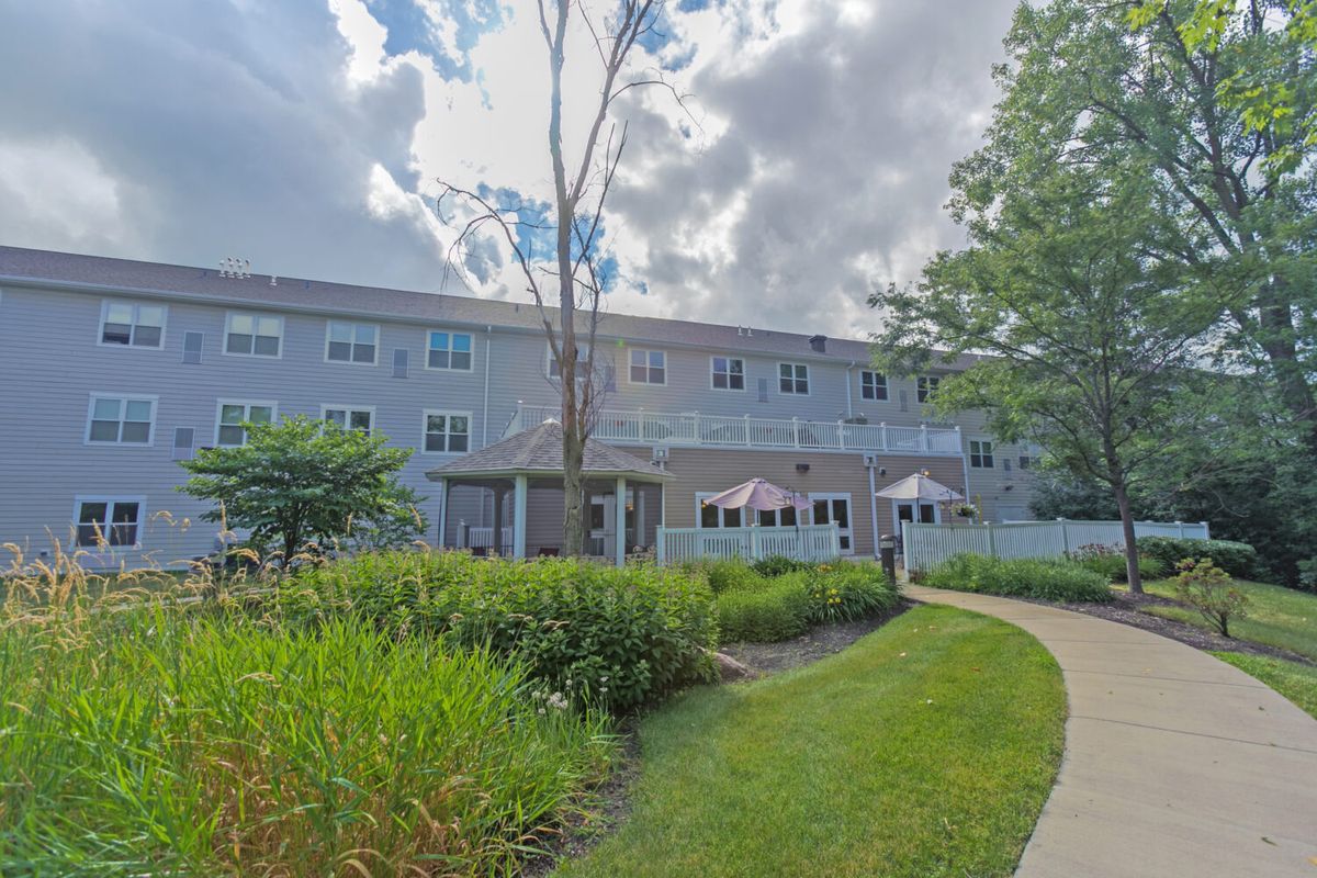 A view of a building surrounded by a well-maintained garden under a cloudy sky.