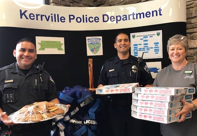 Police officers holding pizza boxes and sandwiches at an event.