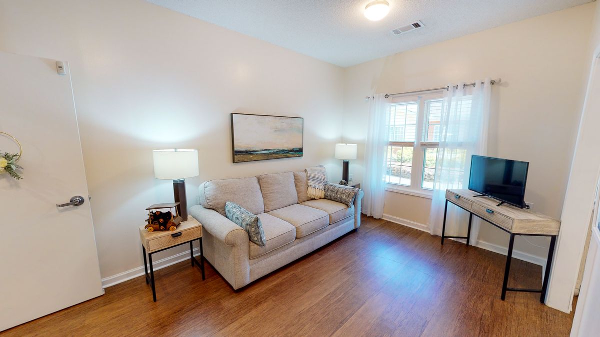 A cozy living room with a comfortable sofa, two lamps, and artwork on the wall.