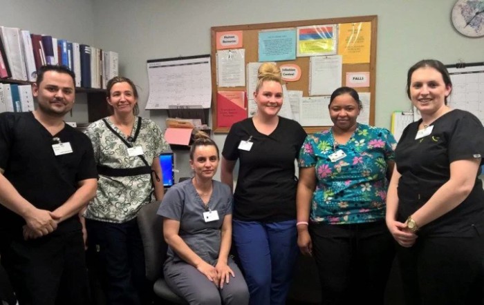 A group of four staff members posing in an office setting.