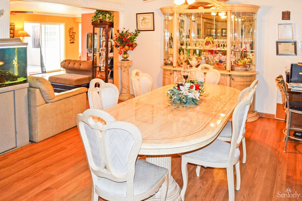 A well-decorated dining room featuring a large table with elegant chairs and a floral centerpiece.