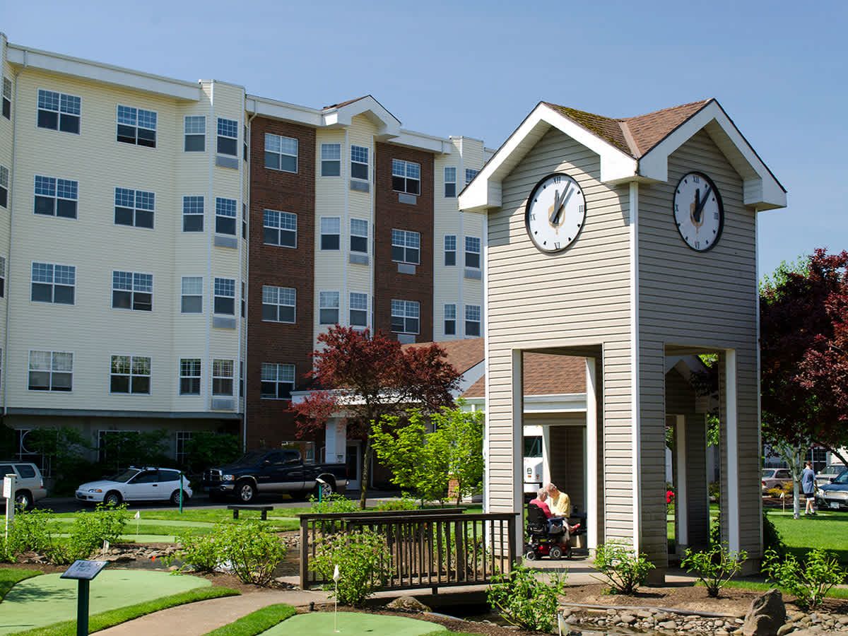 A residential building with a clock tower and garden area.