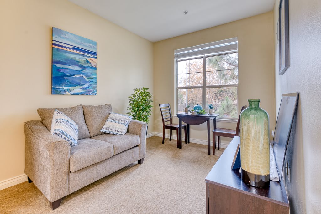 A cozy living room with a sofa, artwork on the wall, and a table by the window.