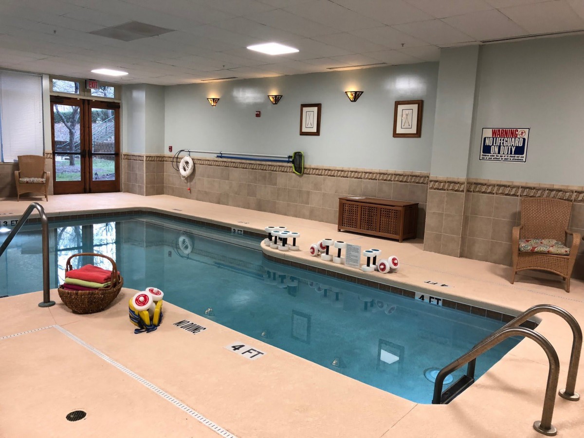 An indoor swimming pool at a hotel with toys and seating areas.