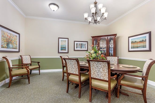 A well-decorated dining room with a large table and elegant chairs beneath a classic chandelier.