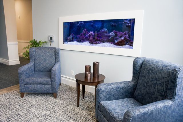 A cozy living room with two armchairs and a wall-mounted aquarium.