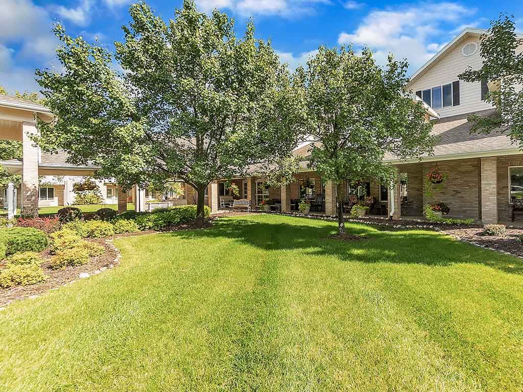 A suburban house with a well-maintained lawn and trees in the yard.