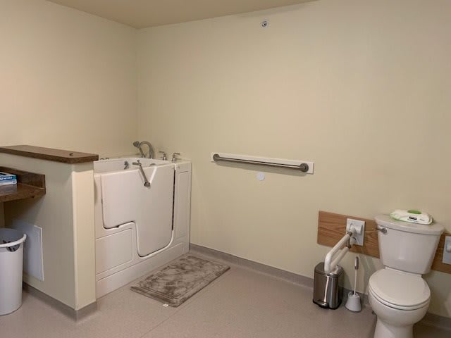 An accessible bathroom with a walk-in tub, grab bar, and toilet.
