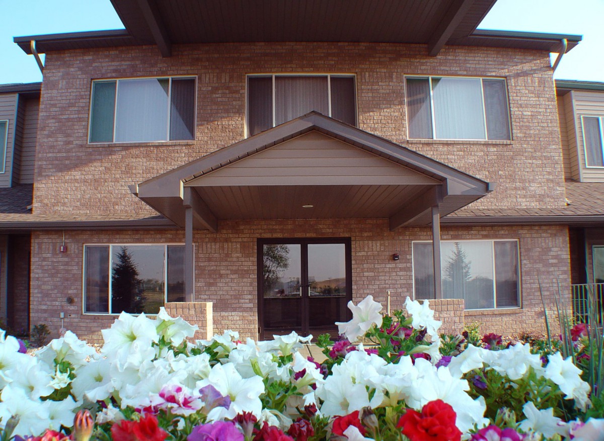 A brick house with colorful flowers in the foreground.