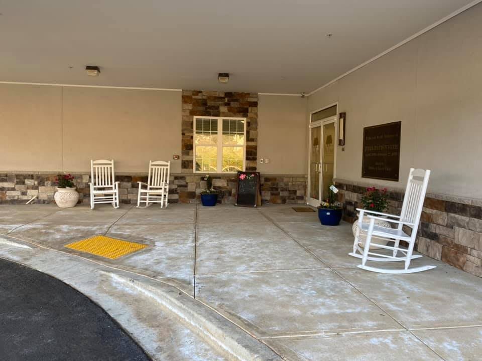 A welcoming porch with rocking chairs and potted plants at a building entrance.