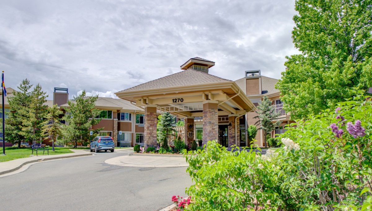 A welcoming building entrance surrounded by lush greenery under a cloudy sky.