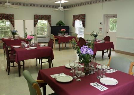 A cozy dining area set up for a meal, featuring elegantly decorated tables with flowers.