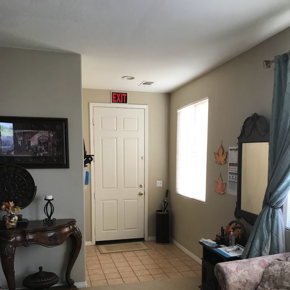 A cozy living room with a view of the front door, decorated with a table, mirror, and curtains.