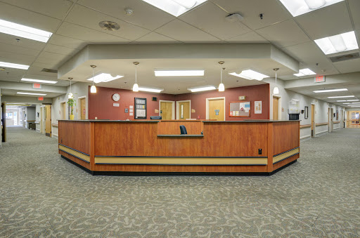 A spacious reception area in a hospital, featuring a wooden front desk and comfortable waiting space.