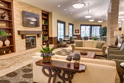A modern and cozy living room featuring a fireplace, comfortable seating, and decorative plants.