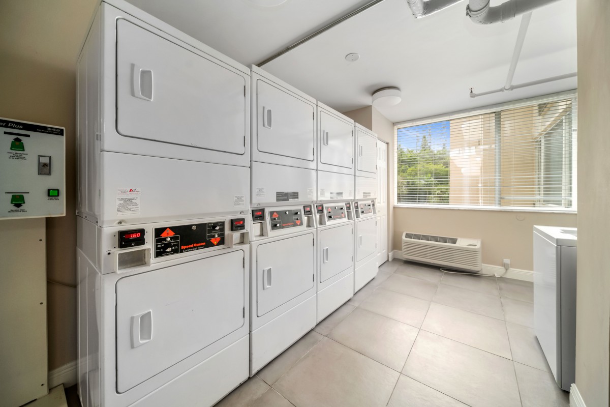 A clean and modern laundry room with stacked washing machines and dryers.