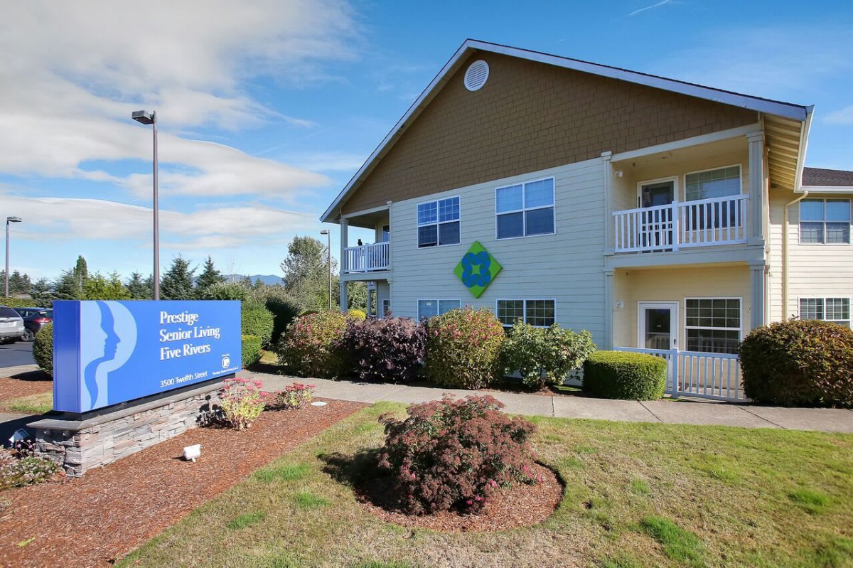 A residential building with a sign and landscaped surroundings on a sunny day.
