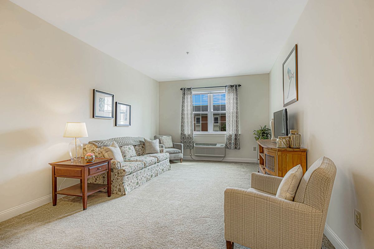 A cozy living room with comfortable seating, a television, and large window.