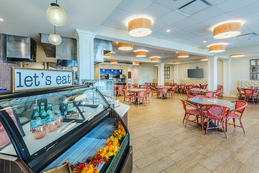 A bright and welcoming dining area featuring cozy seating arrangements and a food display counter.