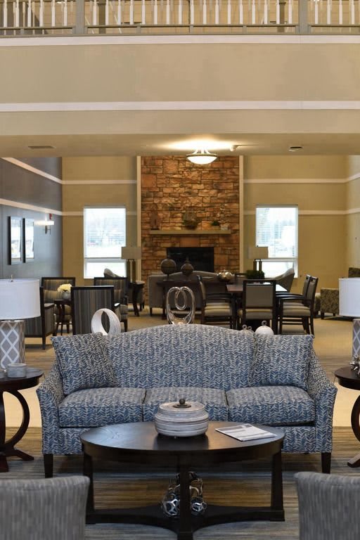 A cozy living room with a central sofa, coffee tables, and a brick fireplace in the background.