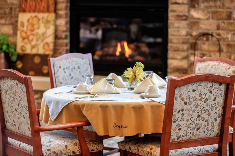 A cozy dining setup with a neatly arranged table near a warm fireplace.
