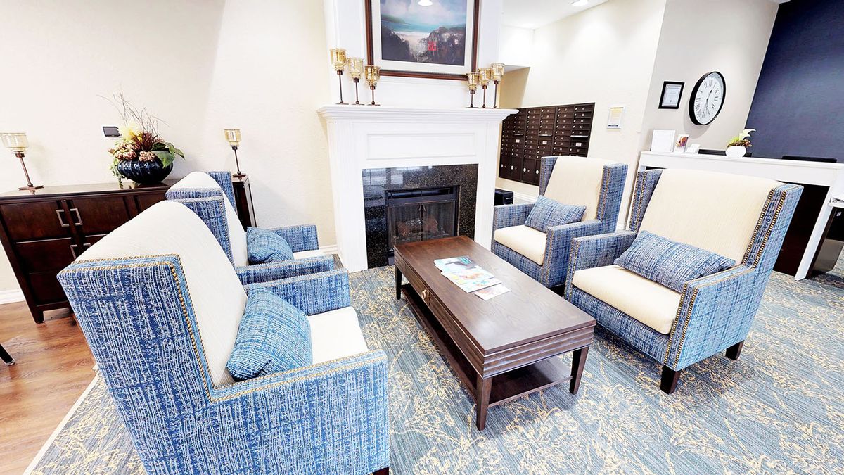A cozy living room with blue armchairs and a coffee table in front of a fireplace.
