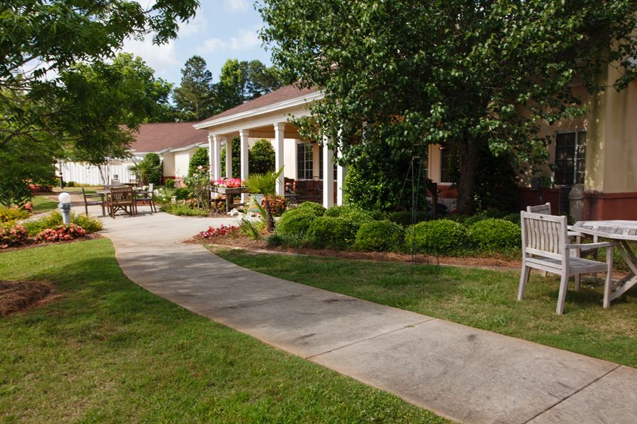 A charming house surrounded by a lush garden with a pathway leading to the entrance.