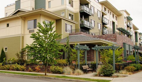 A modern apartment building with well-maintained landscaping and outdoor seating.