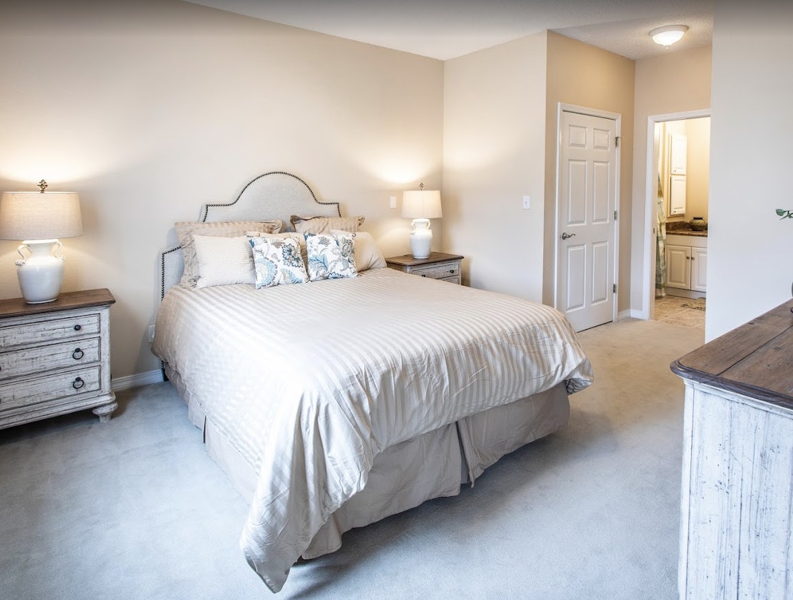 A cozy bedroom with a neatly made bed, two nightstands, and elegant lighting.