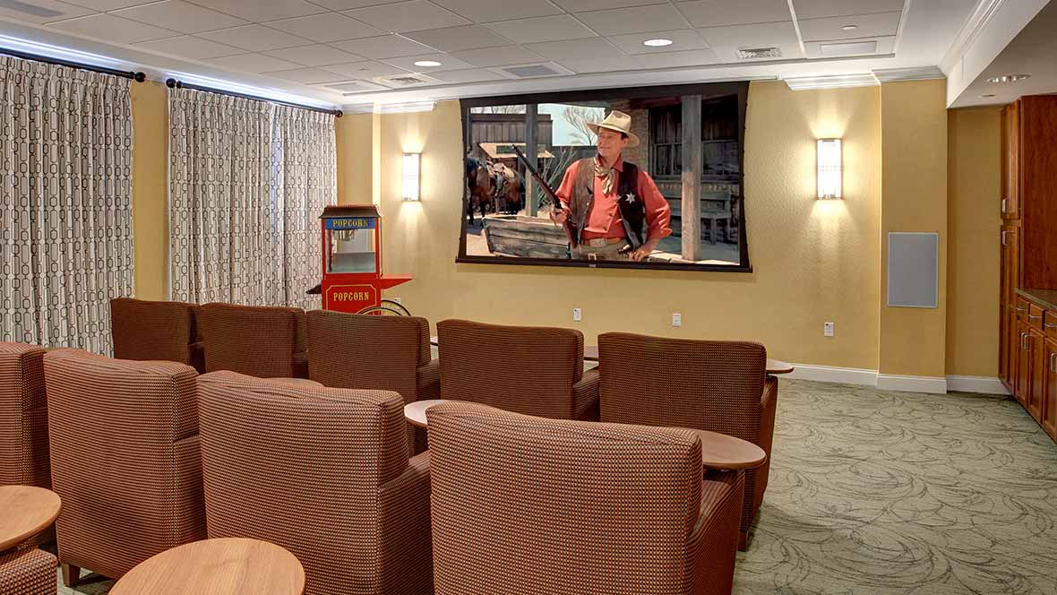 A cozy home theater setup with a large screen displaying a movie, comfortable seating, and a popcorn machine in the corner.