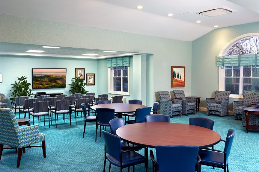A spacious and well-lit meeting room with multiple tables and chairs arranged for a conference or gathering.
