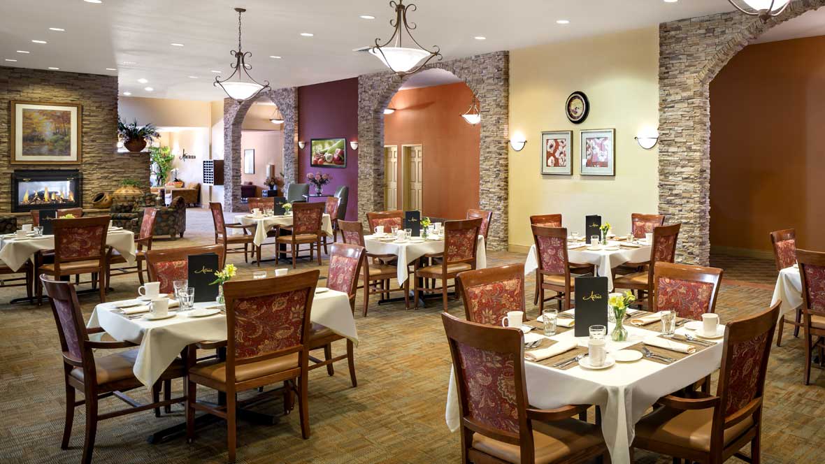 A cozy restaurant dining area with neatly arranged tables and chairs, adorned with elegant lighting and decor.