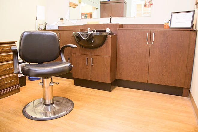 A modern salon with a barber chair and hair wash station.