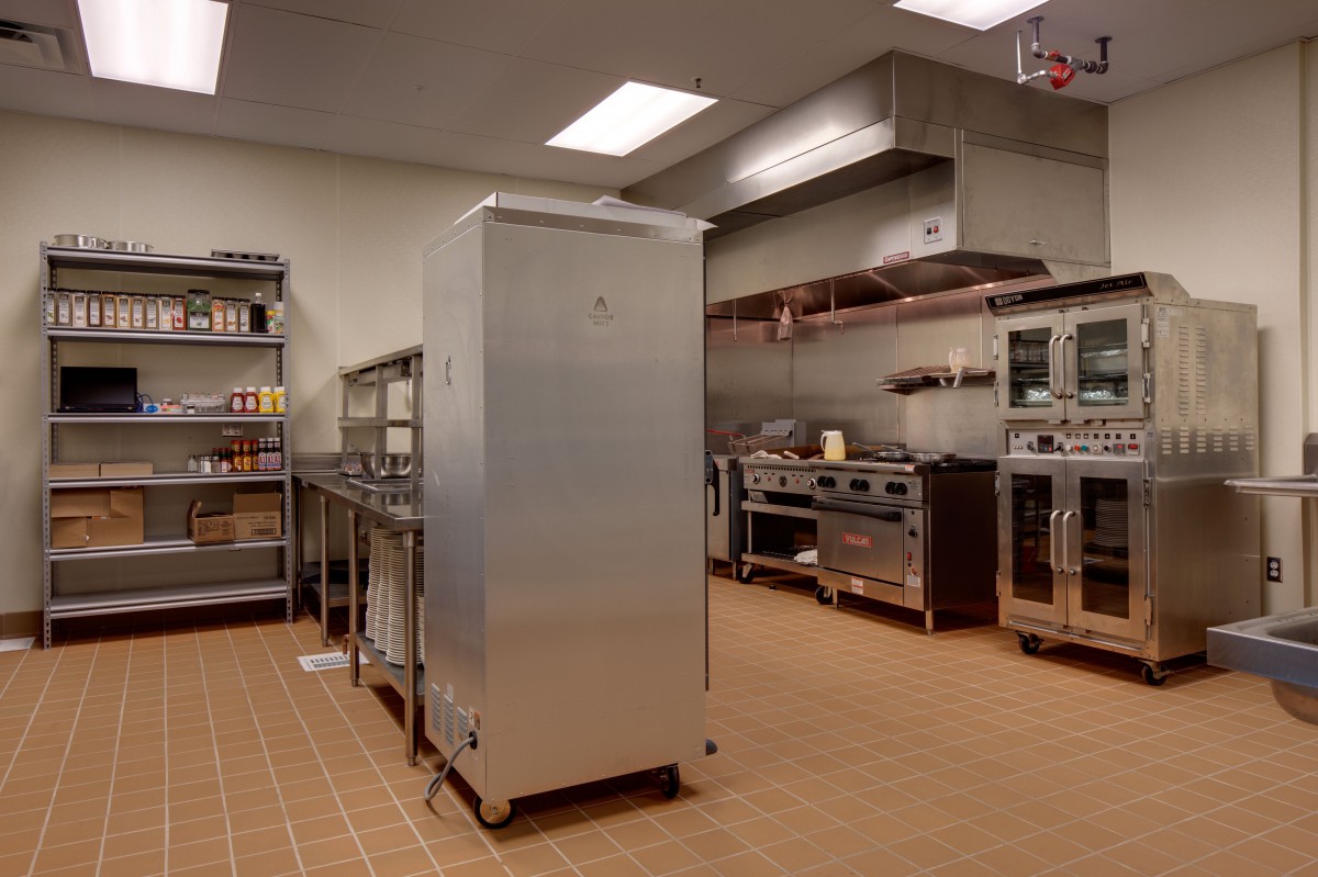 A well-equipped commercial kitchen with stainless steel appliances and storage shelves.