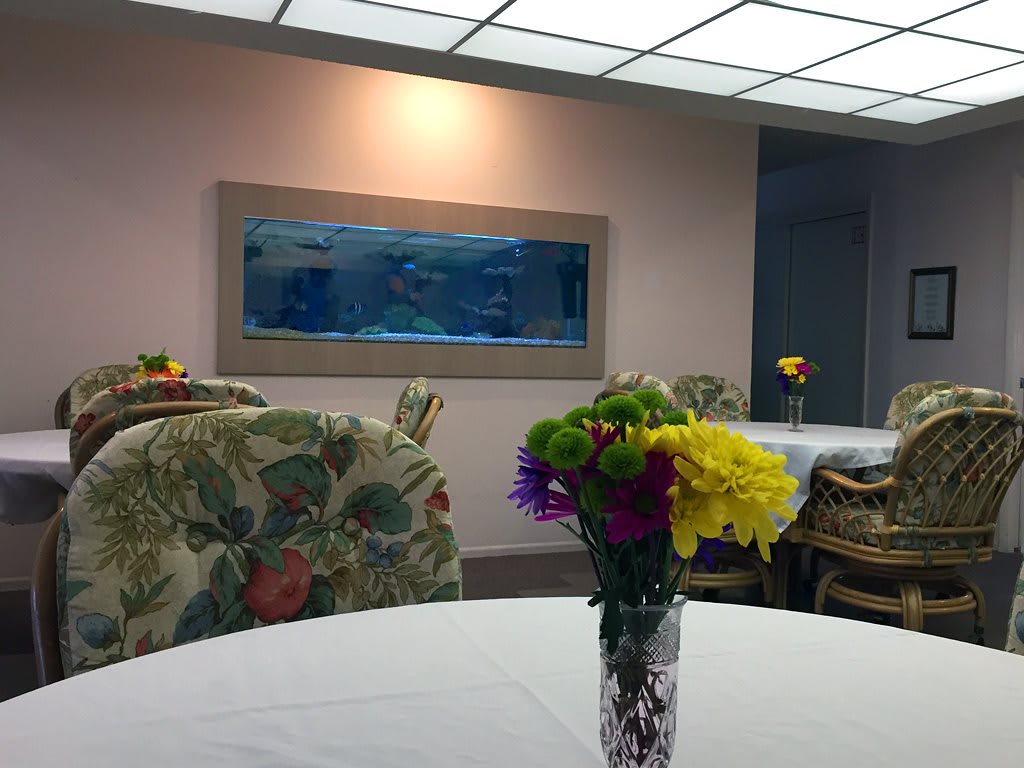 A cozy lounge area featuring an aquarium on the wall and vibrant flowers on the table.