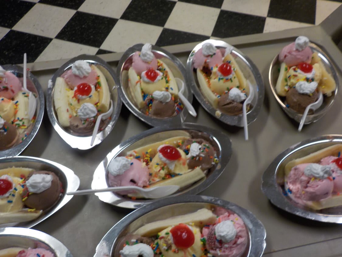 A delightful array of banana splits, each topped with cherries and whipped cream.