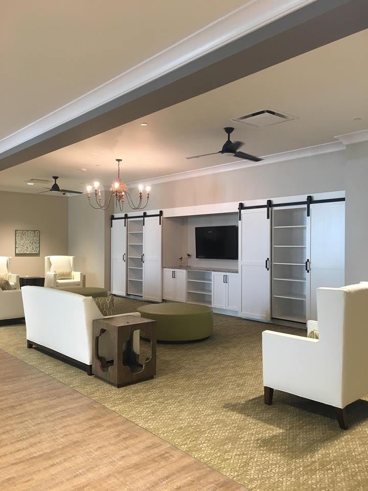 A modern living room with sleek furniture, a television, and stylish barn door cabinets.