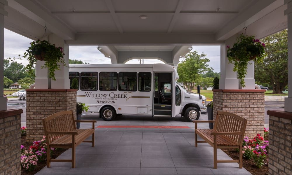 A shuttle bus parked at a building entrance with benches on either side.