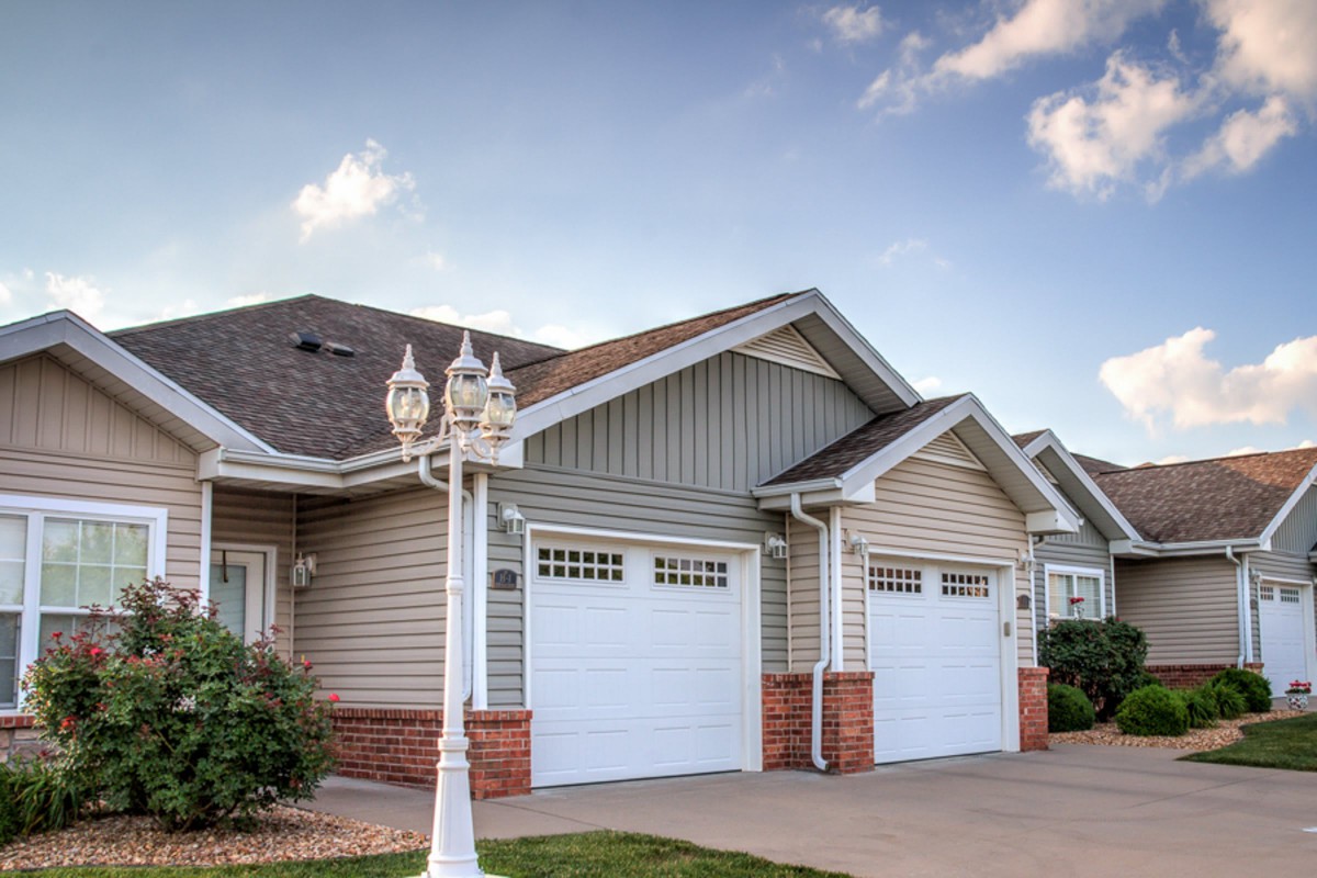 Suburban houses with garages and a lamp post lining the driveway.