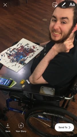 A person in a wheelchair smiling while working on an abstract painting.