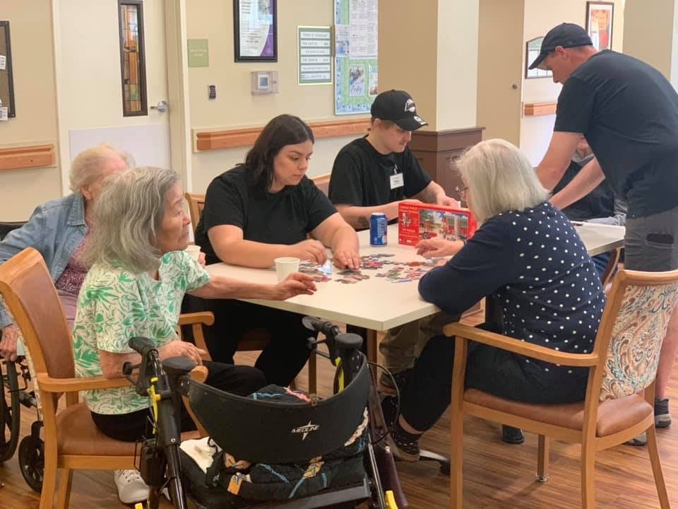 Elderly residents engaging in a card game at a care facility.