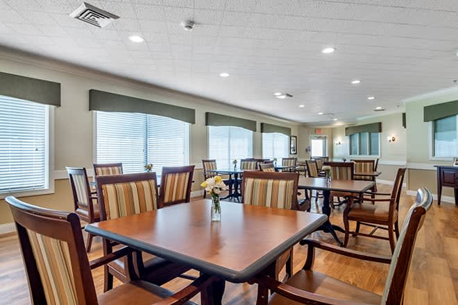 A spacious and well-lit dining room with multiple tables and chairs arranged neatly.